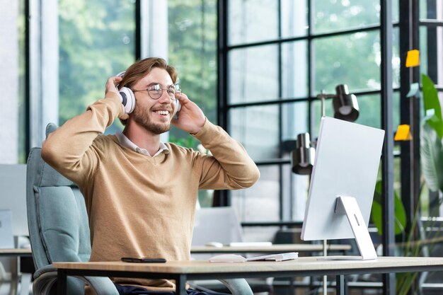 Photo a young male student in headphones studies in the office campus at home in front of a laptop hands