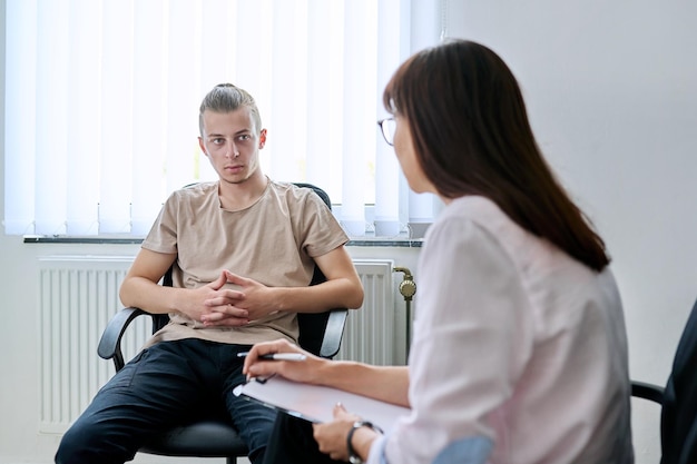 Photo young male student at therapy meeting with college psychologist counselor