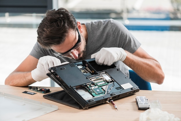 Young male technician fixing computer on wooden desk