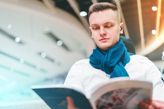 Young male tourist reading magazine in the airport