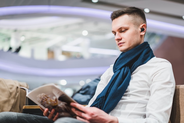 Young male tourist reading magazine in the airport