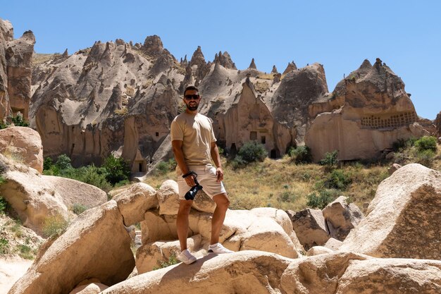 Young male tourist with his camera visiting the fairy chimneys in Cappadocia Turkey