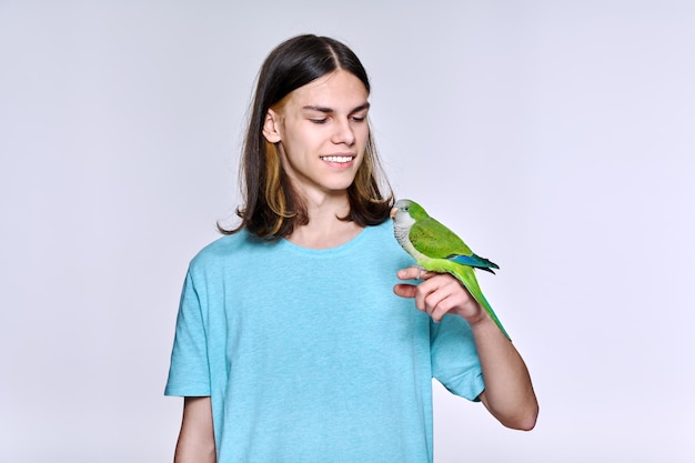 Young male with domestic green Quaker parrot on light studio background