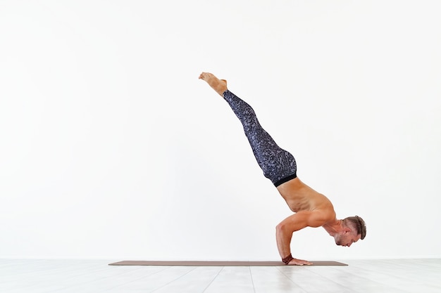 Young man acrobatics gymnastic doing a handstand studio isolated on white  athletic sportsman