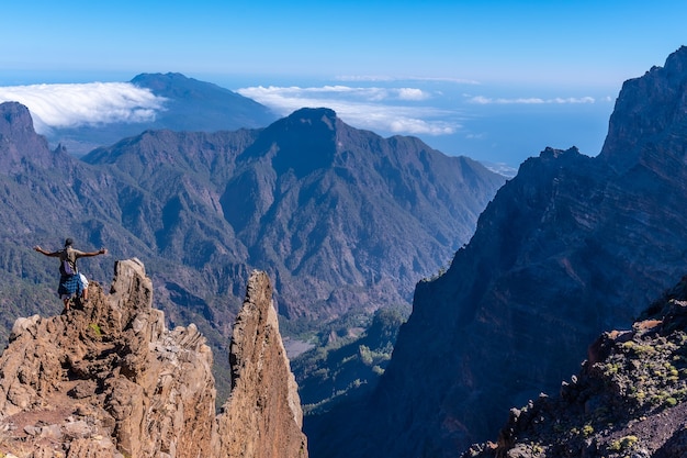 A young man after finishing the trek at the top of the volcano of Caldera de Taburiente near Roque de los Muchachos looking at the incredible landscape, La Palma, Canary Islands. Spain