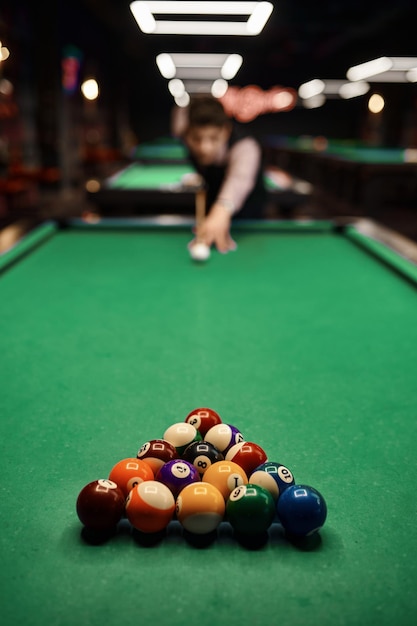 Young man aiming with billiards cue