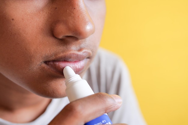 Young man applying moisturising lip balm on lips