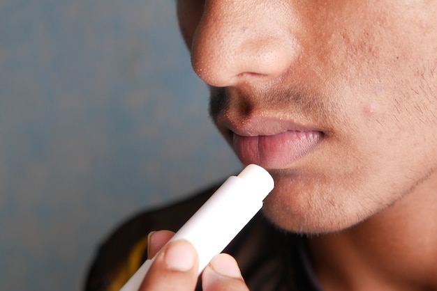 young man applying moisturising lip balm on lips