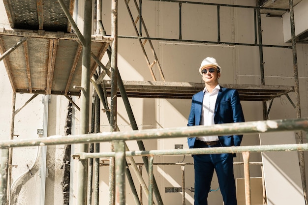 Young man architect or businessman wearing formal suit and hard hat on a construction site