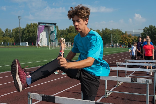 Young man athlete runnner running hurdles at the stadium outdoors