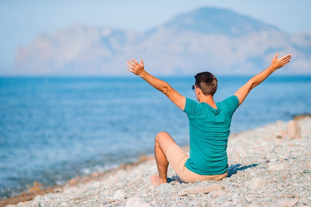 Young man on the beach relaxing with view of mountains