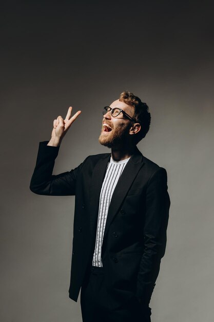 Young man in black jacket with party glasses on color background