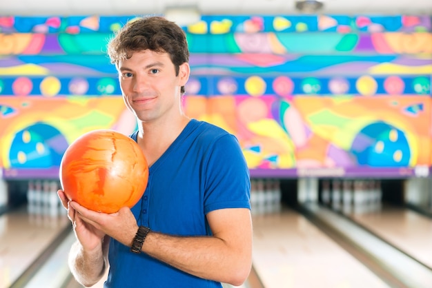 Young man in bowling alley having fun, the sporty man holding a bowling ball in front of the ten pin alley