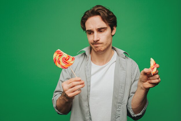 Young man broke piece of lollipop and looks disappointed