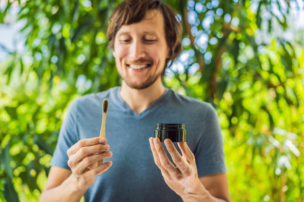 Young man brush teeth using Activated charcoal powder for brushing and whitening teeth Bamboo eco brush