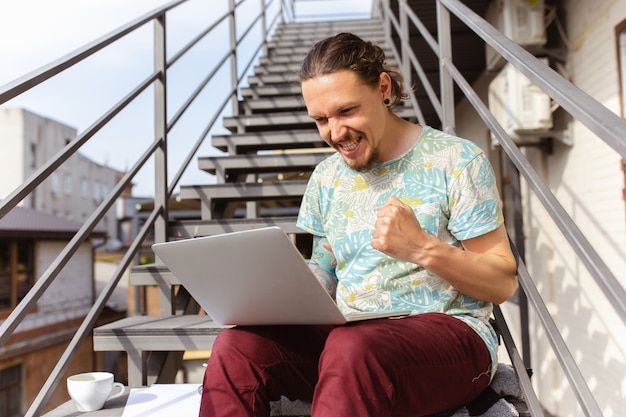 Young man, businessman looking for job using laptop outdoors,