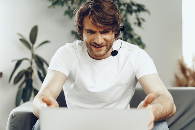 Young man businessman with headset working on laptop from home