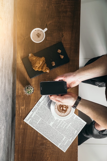 Young man in cafe read newspaper with strong coffee