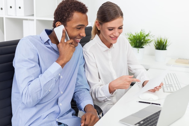 Young man callling while his colleague shows him something