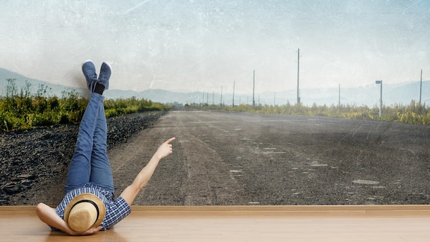 Young man in casual clothes and hat lying on the floor with legs raised up. Mixed media