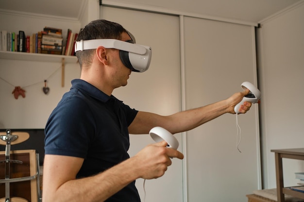 Young man in casual clothes plays virtual games at home Man in virtual reality VR helmet