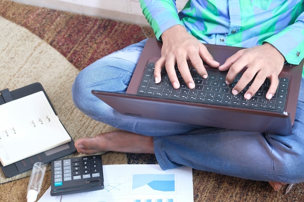 young man in casual dress sitting on floor working from home