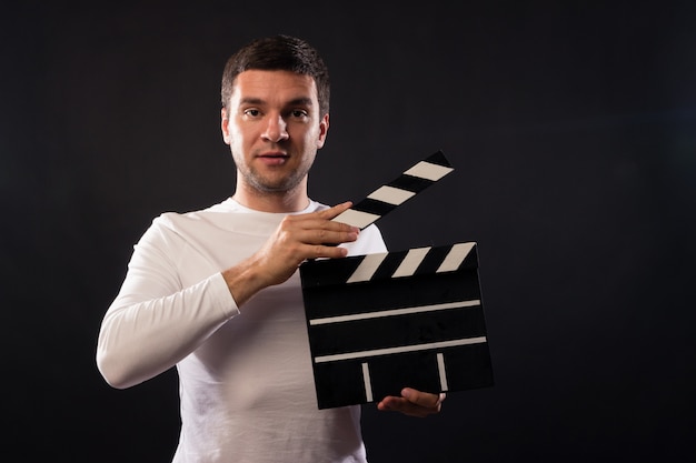 Young man of Caucasian appearance is holding a clapperboard.