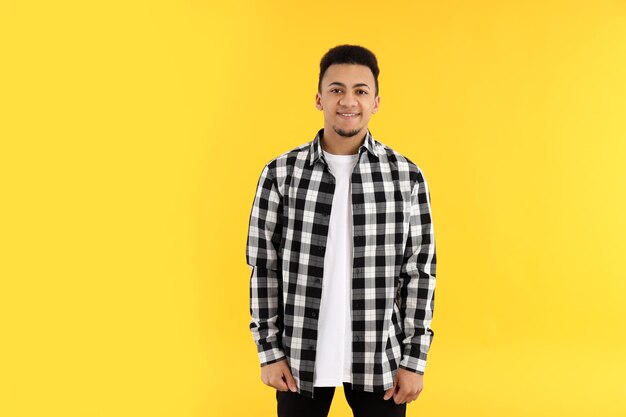 Young man in checkered shirt on yellow background