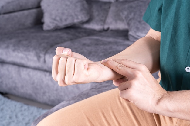 Young man checking pulse while sitting on sofa at home