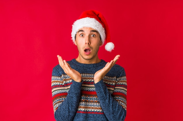 Young man on christmas day doubting and shrugging shoulders in questioning gesture.