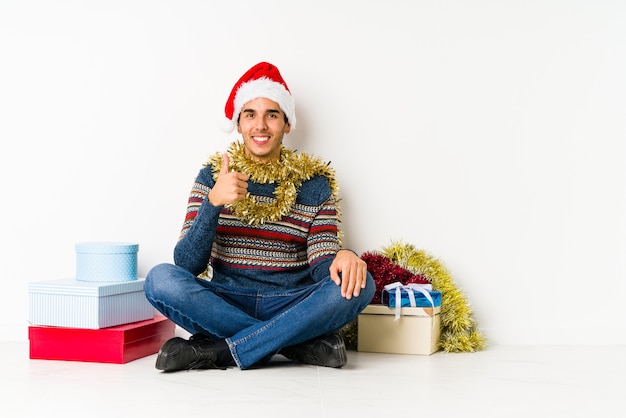 Young man on christmas day laughs out loudly keeping hand on chest.