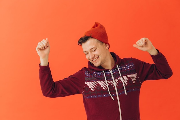 A young man in a Christmas kigurumi and a knitted hat on a colored background