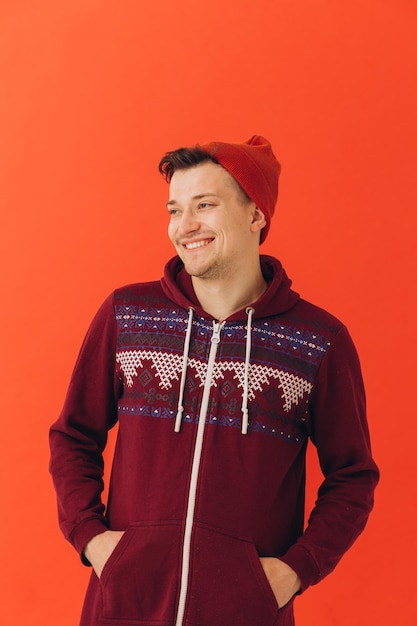 Young man in Christmas sweater and hat on color backgroundxA