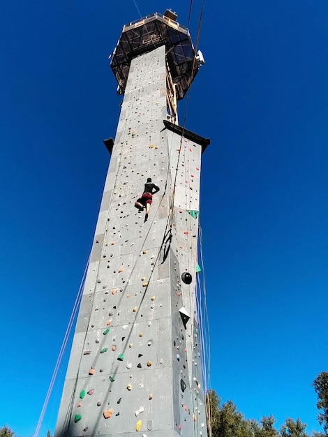 A young man climbs the wall for climbing in special equipment View from below