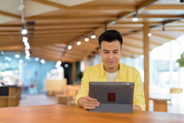 Young man at coffee shop using digital tablet computer