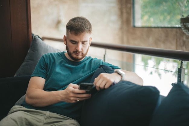 Young man on the couch in the hall sitting and looking at the phone