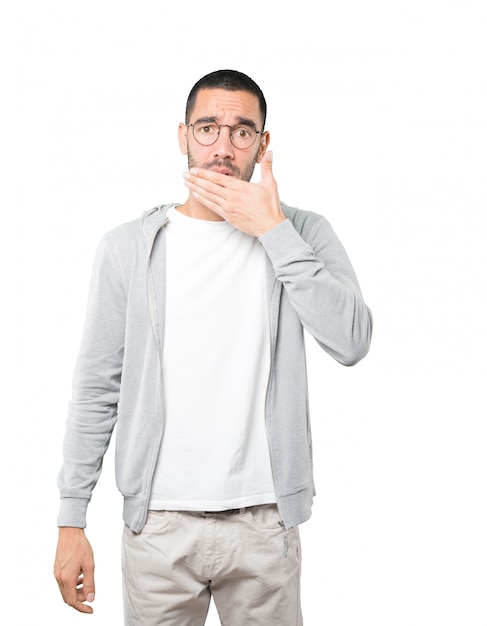 Young man covering his mouth with his hands