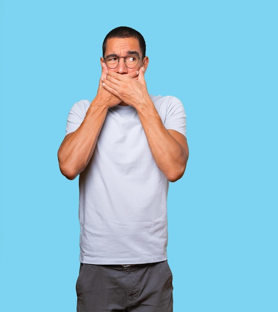 Young man covering his mouth with his hands