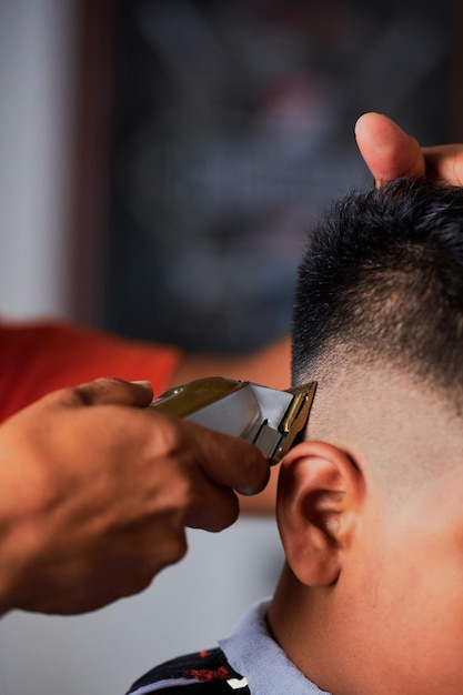 Young man cutting hair of boy in barbershop