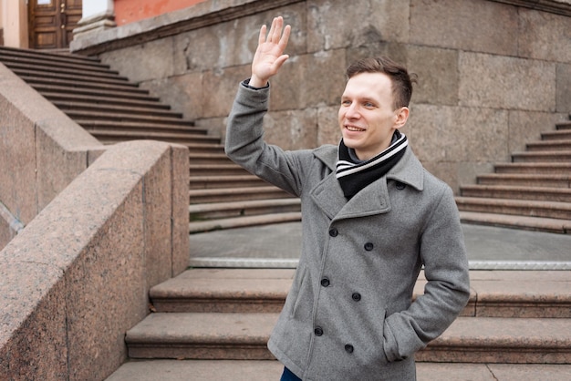 Young man in dark clothes on street Caucasian guy in gray coat smiles