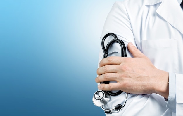 Young man doctor holding a stethoscope on background