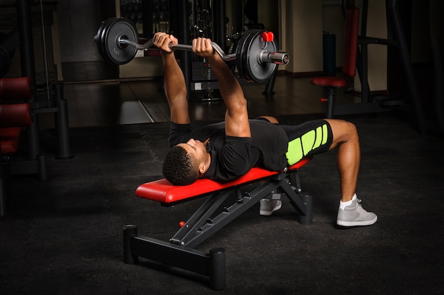 Young man doing arms bench french press workout in gym