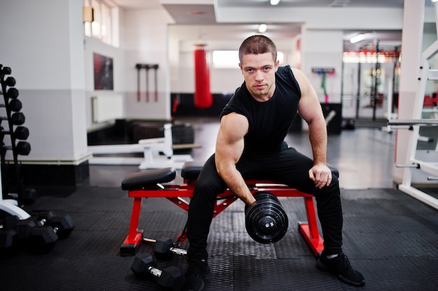 Young man doing exercises and working hard in gym and enjoying his training process.