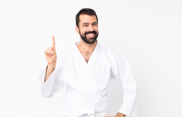 Young man doing karate over isolated  showing and lifting a finger in sign of the best