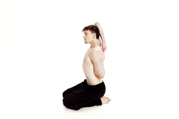 Young man doing yoga exercises studio shot on white background