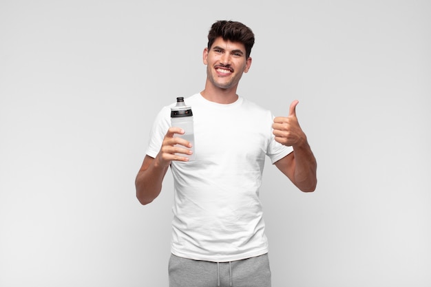 Young man drinking water and giving thumb up