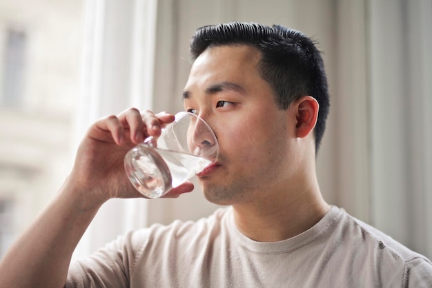 young man drinks a glass of water