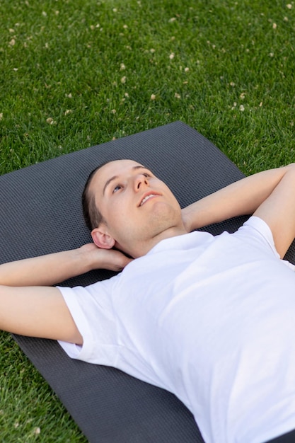 Young man enjoying the resting time in the garden looking at the clear sky on a white tshirt in the park