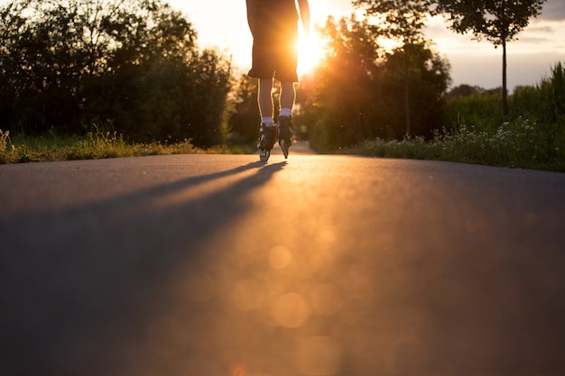 Young man enjoying roller skating on the bicycle path during lovely summer sunset