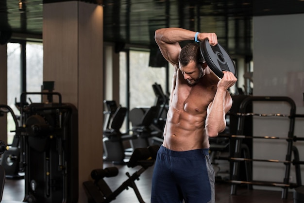 Young Man Exercising Abdominal Muscles With Weights In A Modern Fitness Club